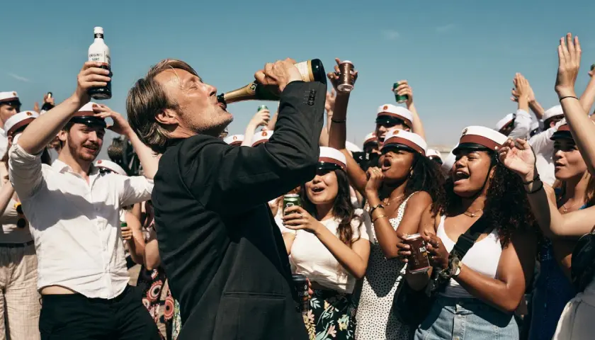 Mads Mikkelsen dricker ur en champagneflaska, omgiven av glada studenter med studentmössor. En runda till recension av firandet.