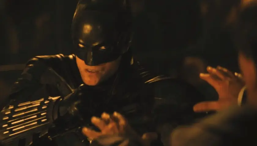 Batman i mörk dräkt, redo för strid i en av filmerna med Batman. En hand syns i förgrunden.