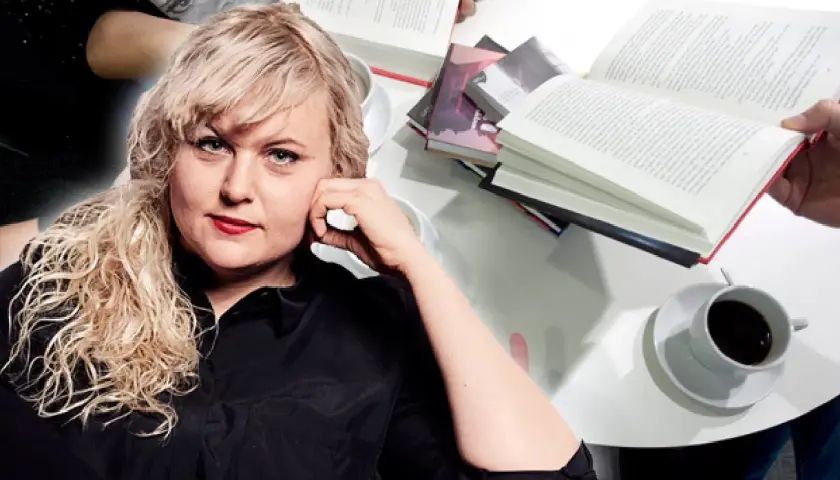 Johanna Thydell sitter vid ett bord med böcker och kaffe.