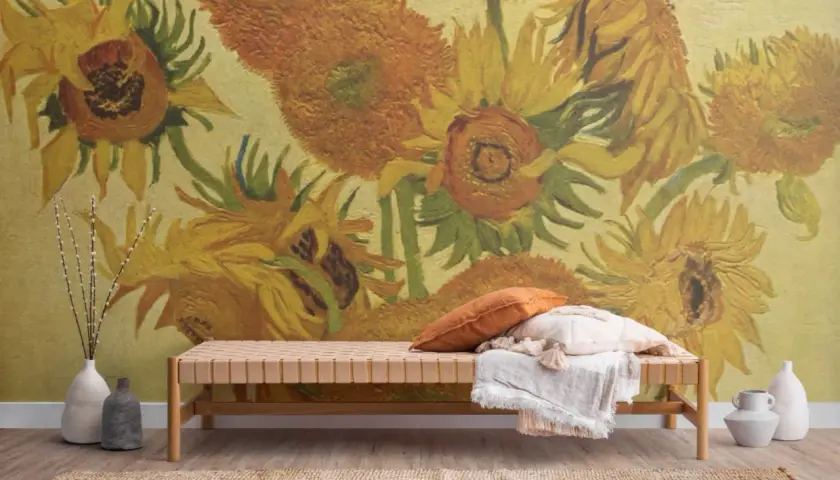 En bänk med kuddar framför en väggmålning inspirerad av Van Goghs solrosor. En vas med kvistar står till vänster.