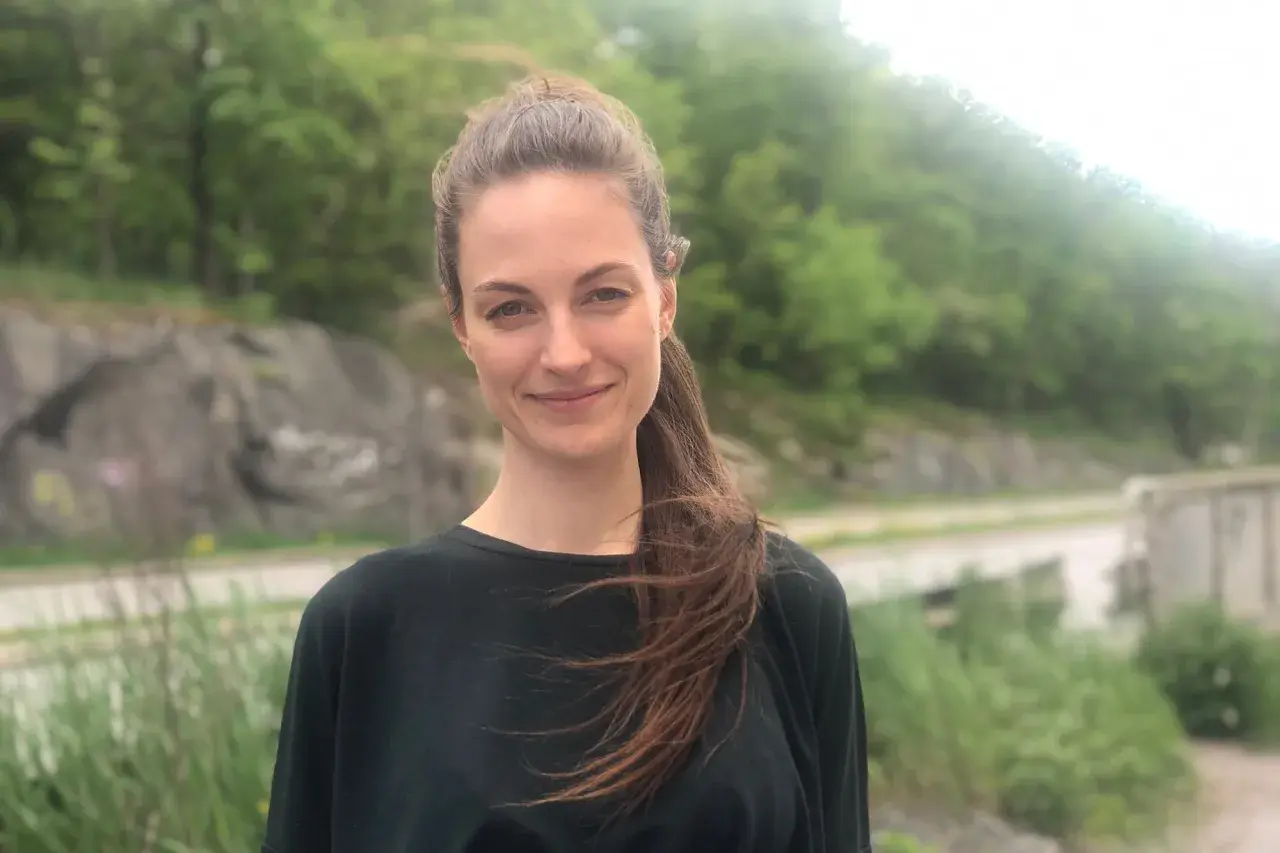 Petra Wahlgren ler mot kameran utomhus, med en grönskande bakgrund.