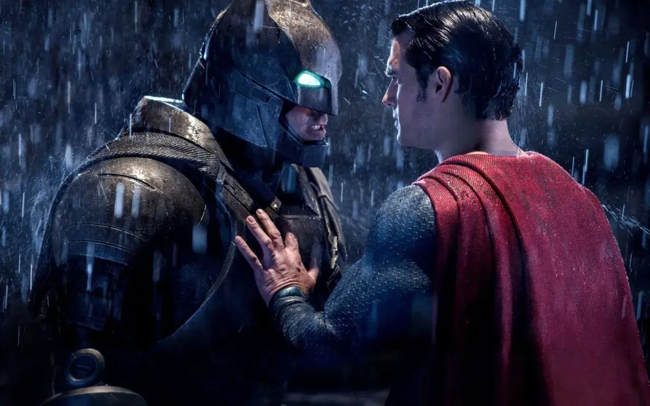 Superman möter en regnig Batman i en tung rustning. Det ser ut som att Batman har varit Batman länge.