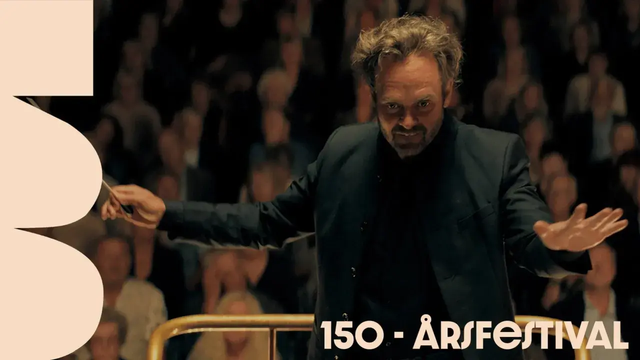 Dirigenten leder orkestern med passion, som om han vore med i rollistan i Hugo Cabret. Publiken ser på.