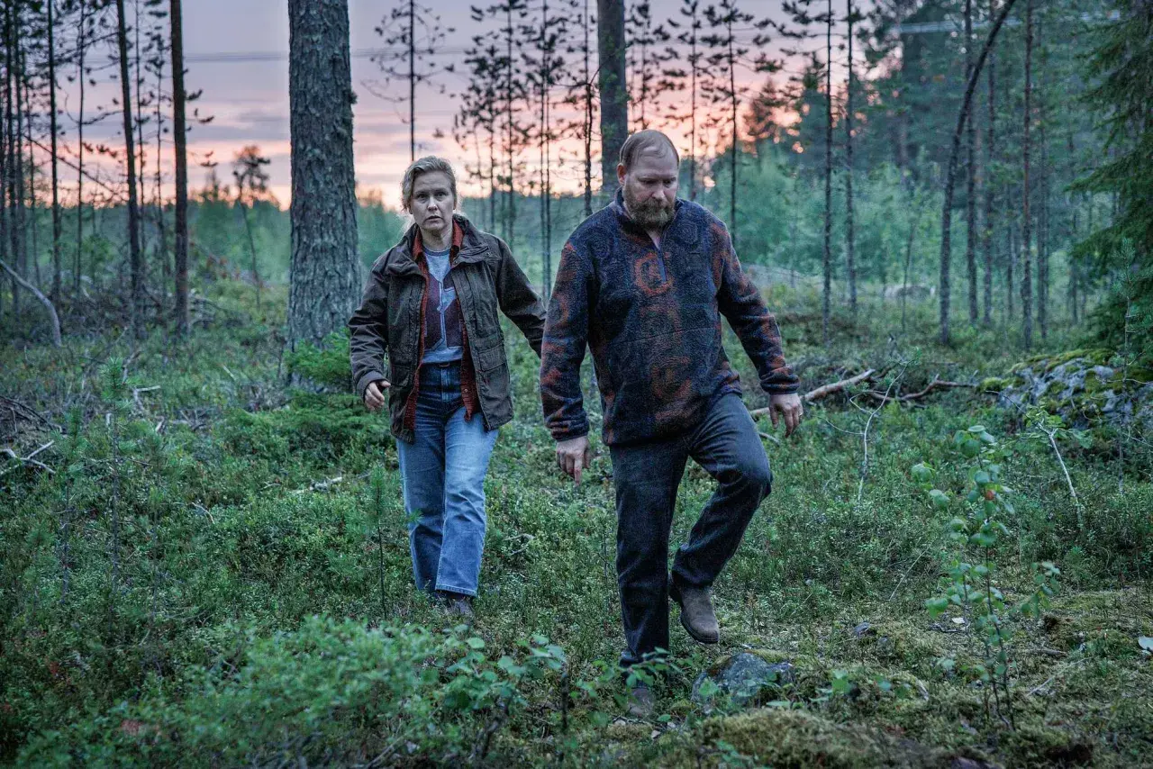 Två personer går genom en skog i skymningen. Det är en scen från Vargasommar del 2.