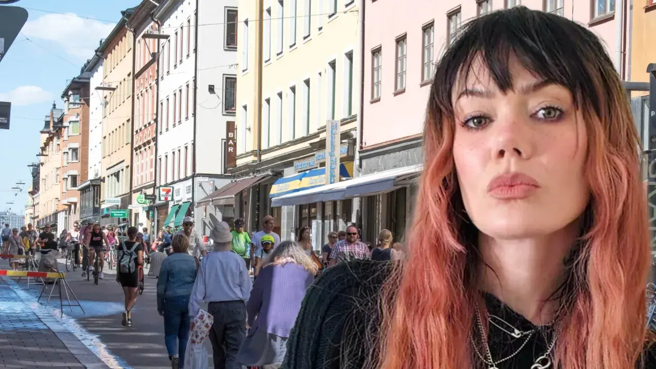 En kvinna med rosa hår poserar framför en livlig svensk stadsgata. Kanske är hon på väg att ta "little jinder expressen" till nästa äventyr.