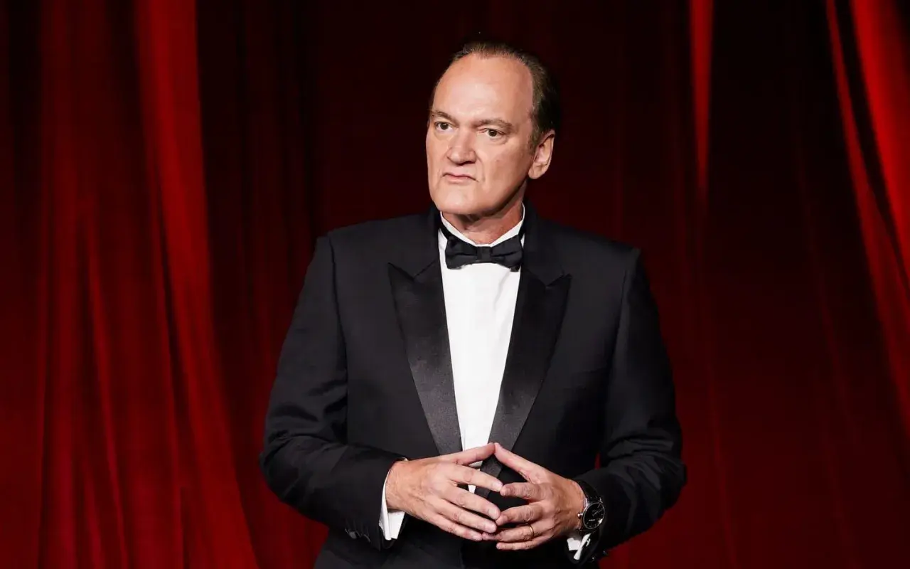 Quentin Tarantino, ikonen bakom ikoniska tarantino filmer, i en elegant smoking framför en röd ridå.
