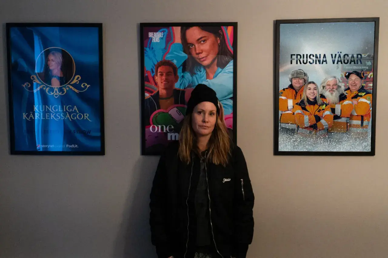 Therese Lundberg står framför tre filmaffischer: "Kungliga Kärlekssagor", "One More" och "Frusna Vägar".