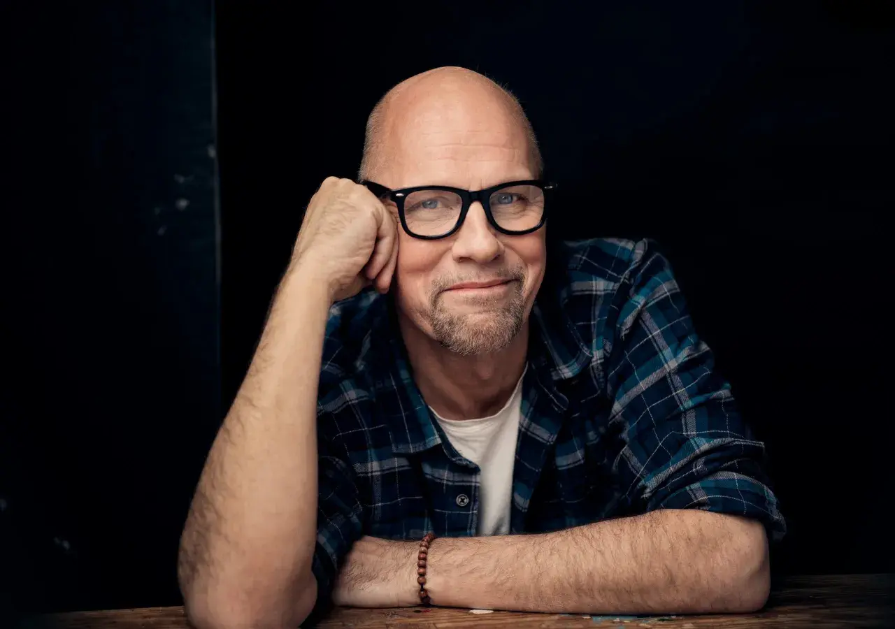 Tomas Tivemark, en skallig man med glasögon och rutig skjorta, lutar sig mot sin hand.
