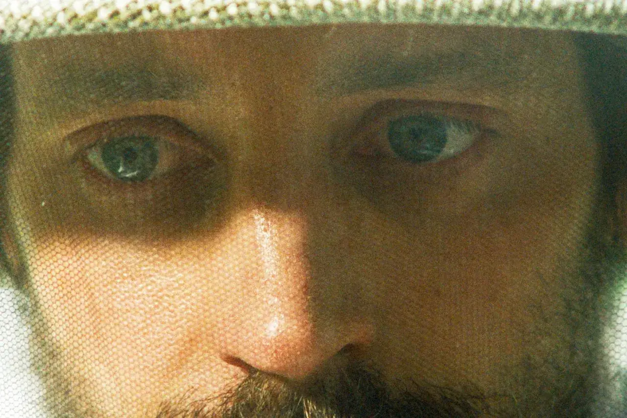 Närbild på biodlarens ansikte genom slöjan. En intensiv blick från biodlaren film.