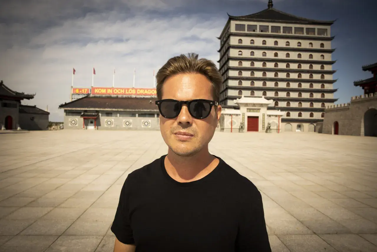 Christian Daun med solglasögon framför en asiatisk byggnad.