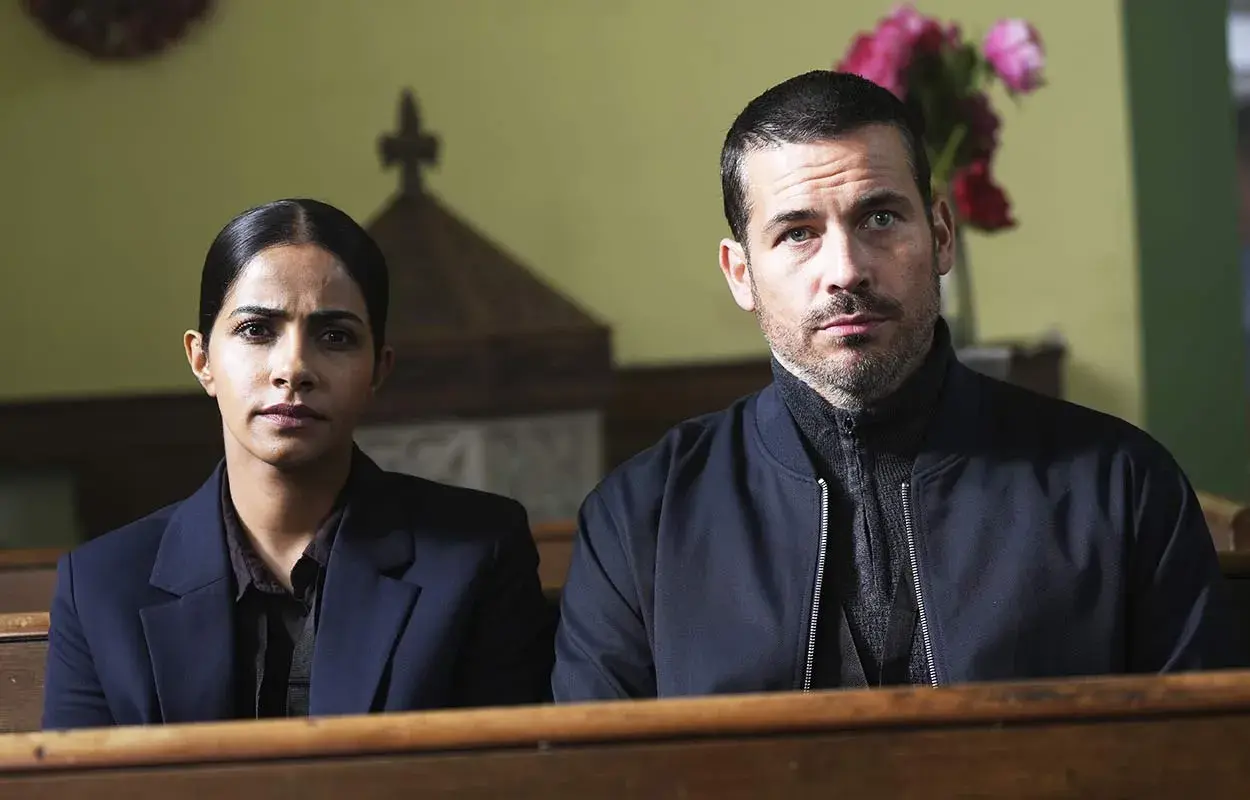 Två utredare sitter i en kyrkbänk. En brittisk kriminalserie som du kan se på SVT Play.