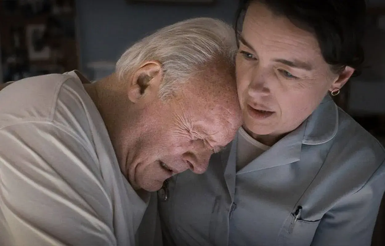 Anthony Hopkins kämpar med demens, hans ansikte uttrycker smärta medan en kvinna tröstar honom.