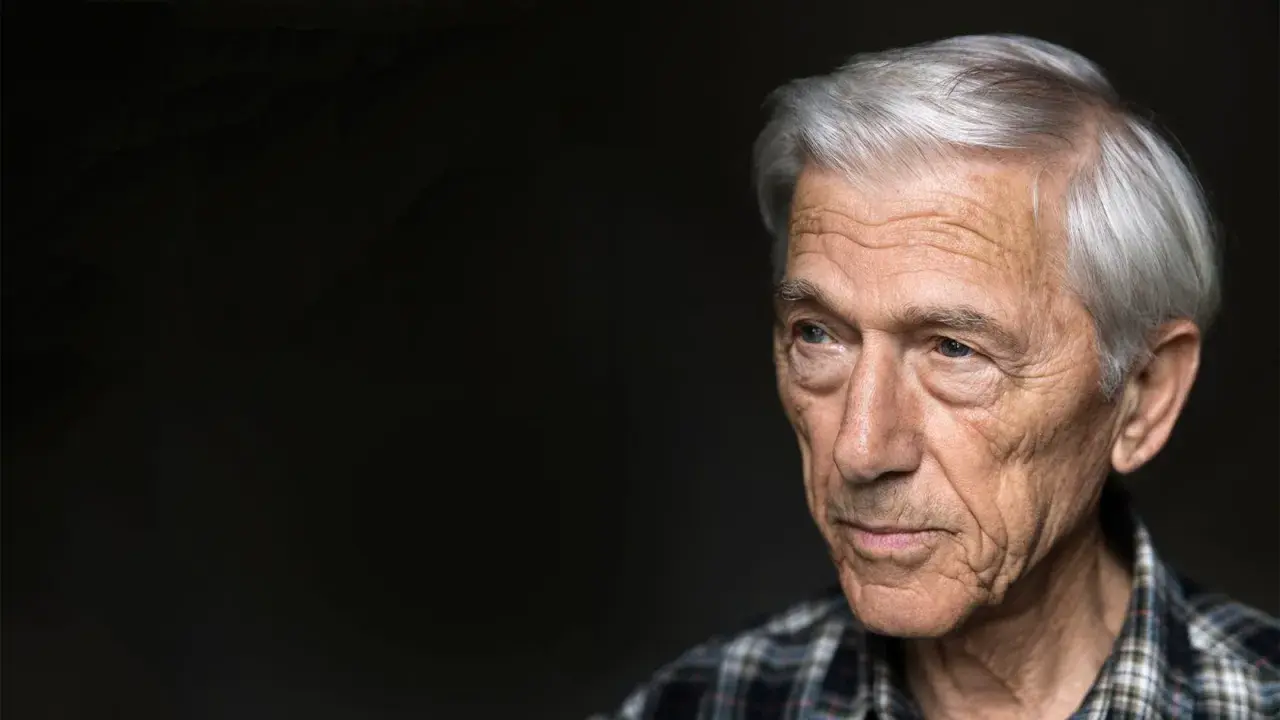 Porträtt av en äldre man med grått hår och rynkor, Theodor Kallifatides, som blickar åt sidan mot en mörk bakgrund.