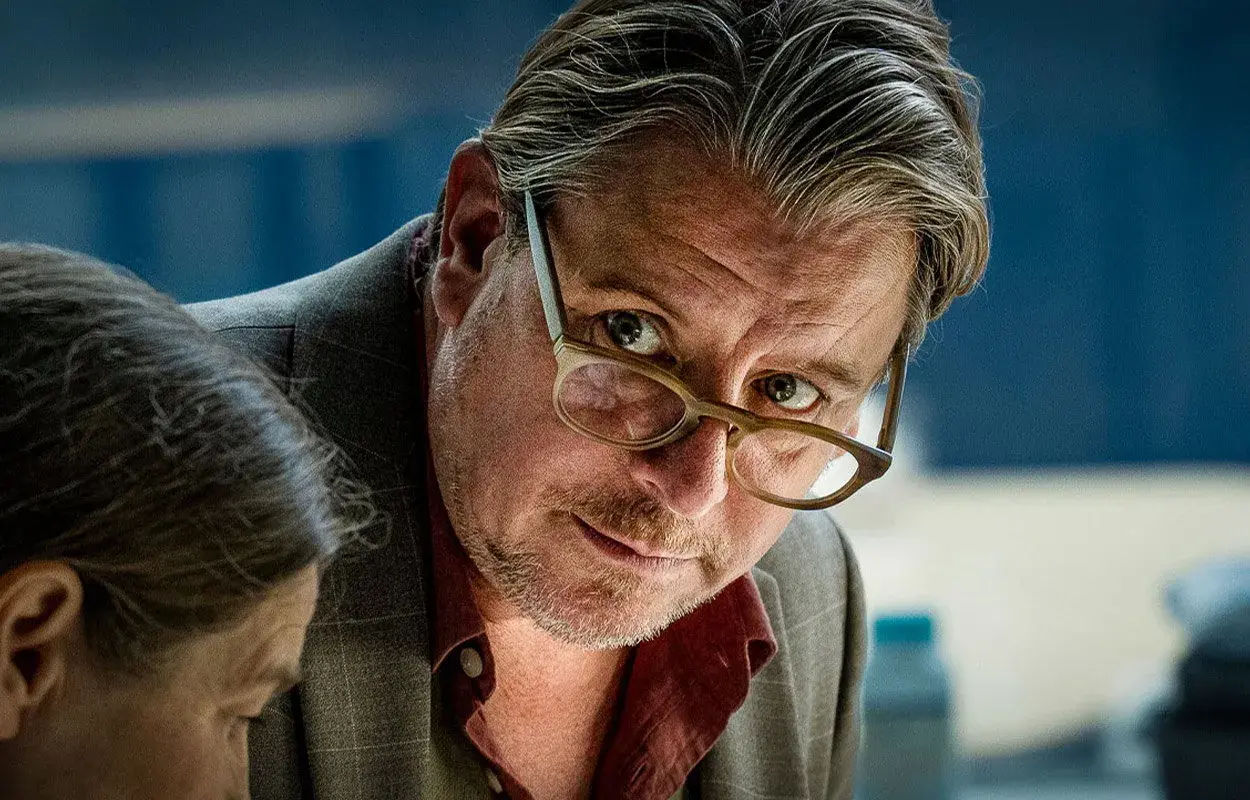 En man med glasögon lutar sig framåt, intensiv blick. En ny dansk serie på TV4.