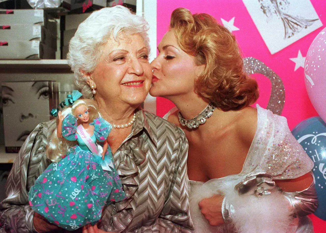 Ruth Handler, skaparen av Barbie, får en kyss av en ung kvinna. Barbie-dockan syns i bilden.