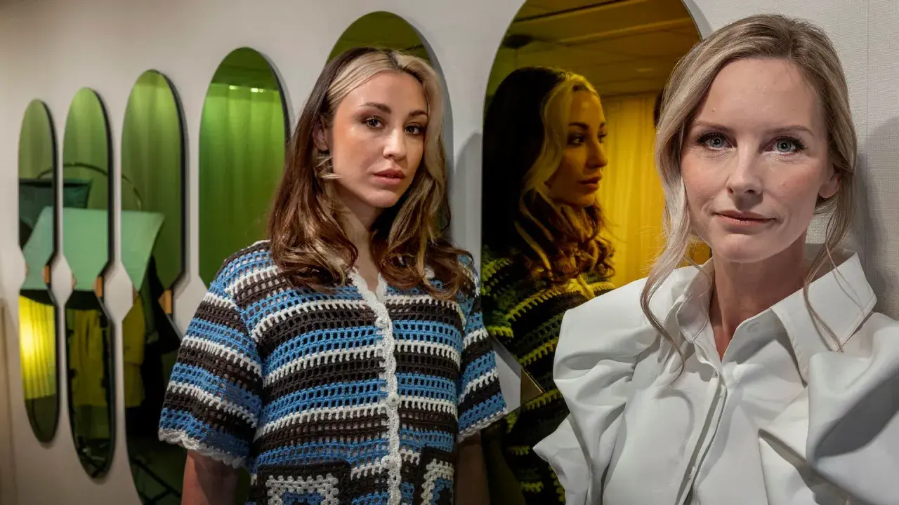 Två kvinnor poserar framför gröna speglar. Den ena bär en virkad tröja, den andra en vit skjorta. Kanske en scen från en emelie schepp serie?