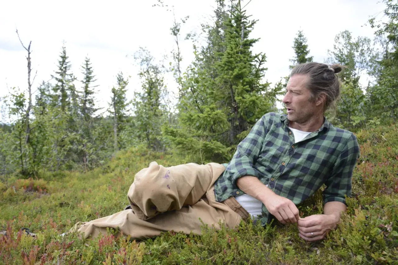 Frida Torgeby vilar i skogen, omgiven av blåbärsris och granar.