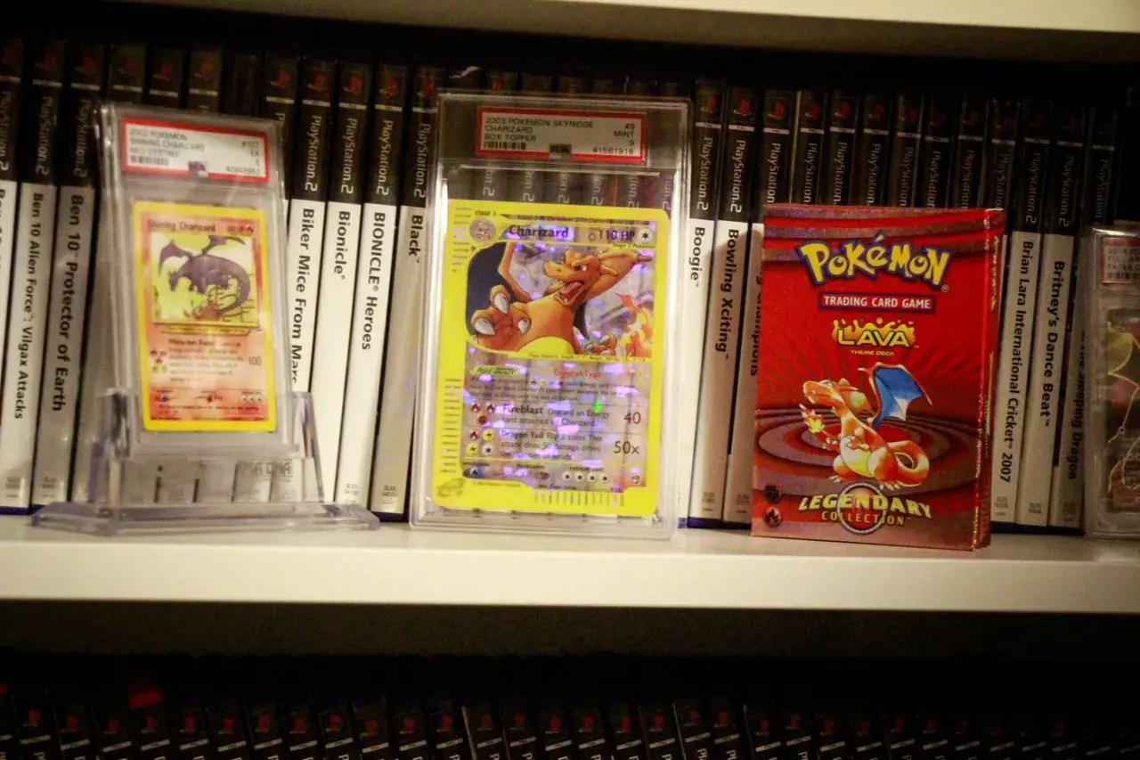 Pokémon-kort och en Pokémon-kortlek på en hylla, bland andra samlarobjekt.