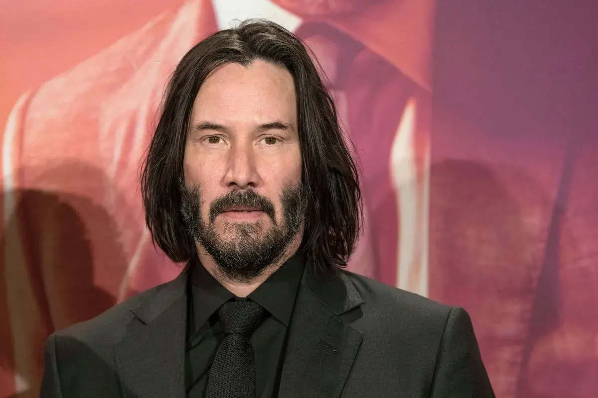 Keanu Reeves, som spelade Neo i Matrix, bär en svart kostym och slips.