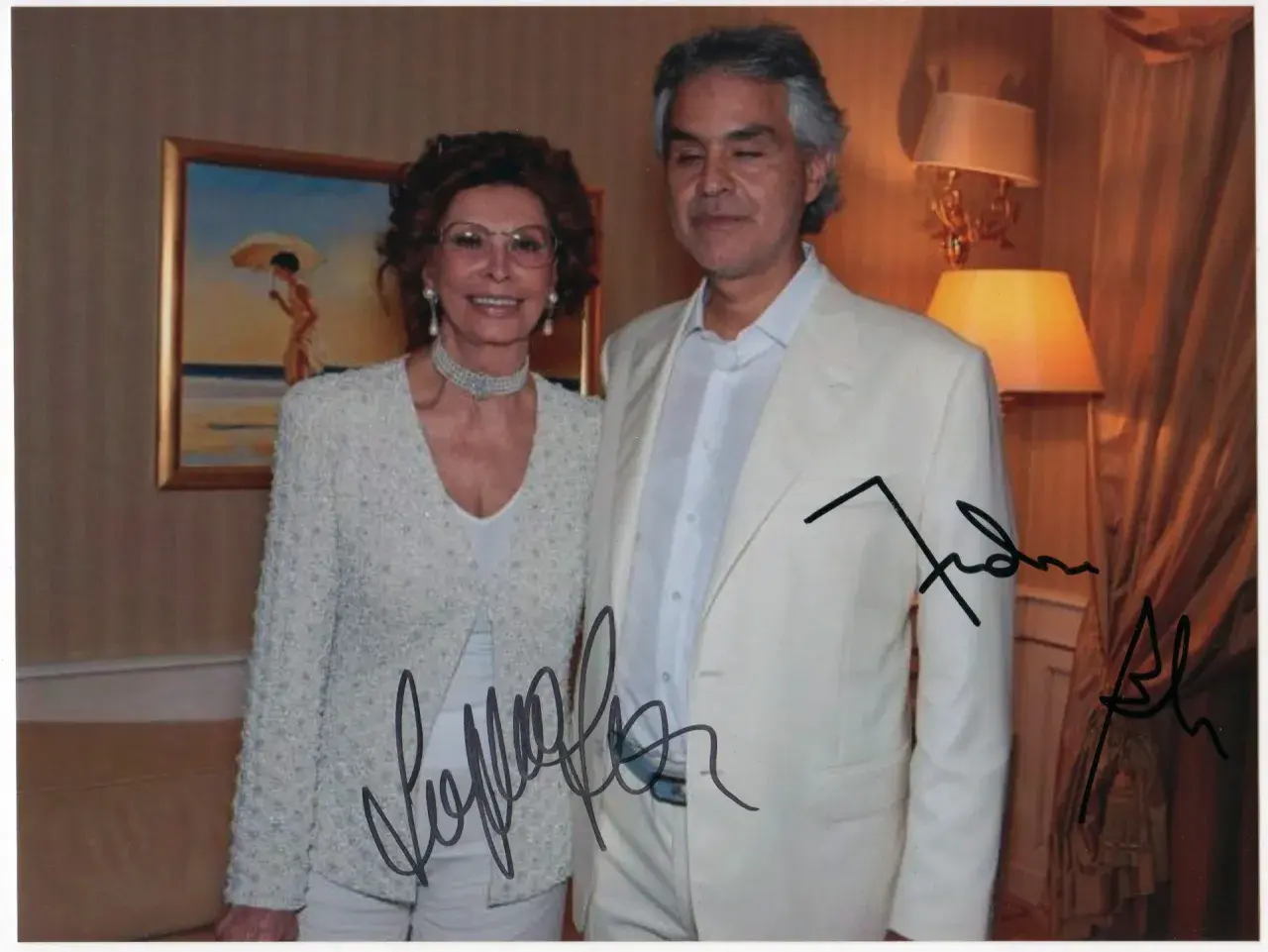 Sophia Loren and Andrea Bocelli pose for a photo, both with autographs on the image.