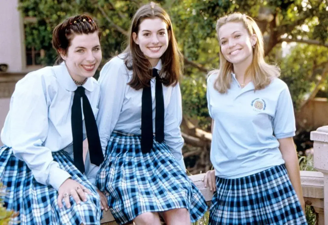 Tre glada tjejer i skoluniformer, som från en prinsessas dagbok 3. De ler mot kameran utomhus.
