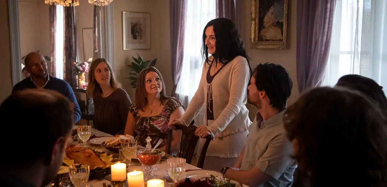 En familj samlas runt ett middagsbord, kanske för en högtidlig stund som i Knutby (tv-serie). Ljusen flimrar och maten är framdukad.