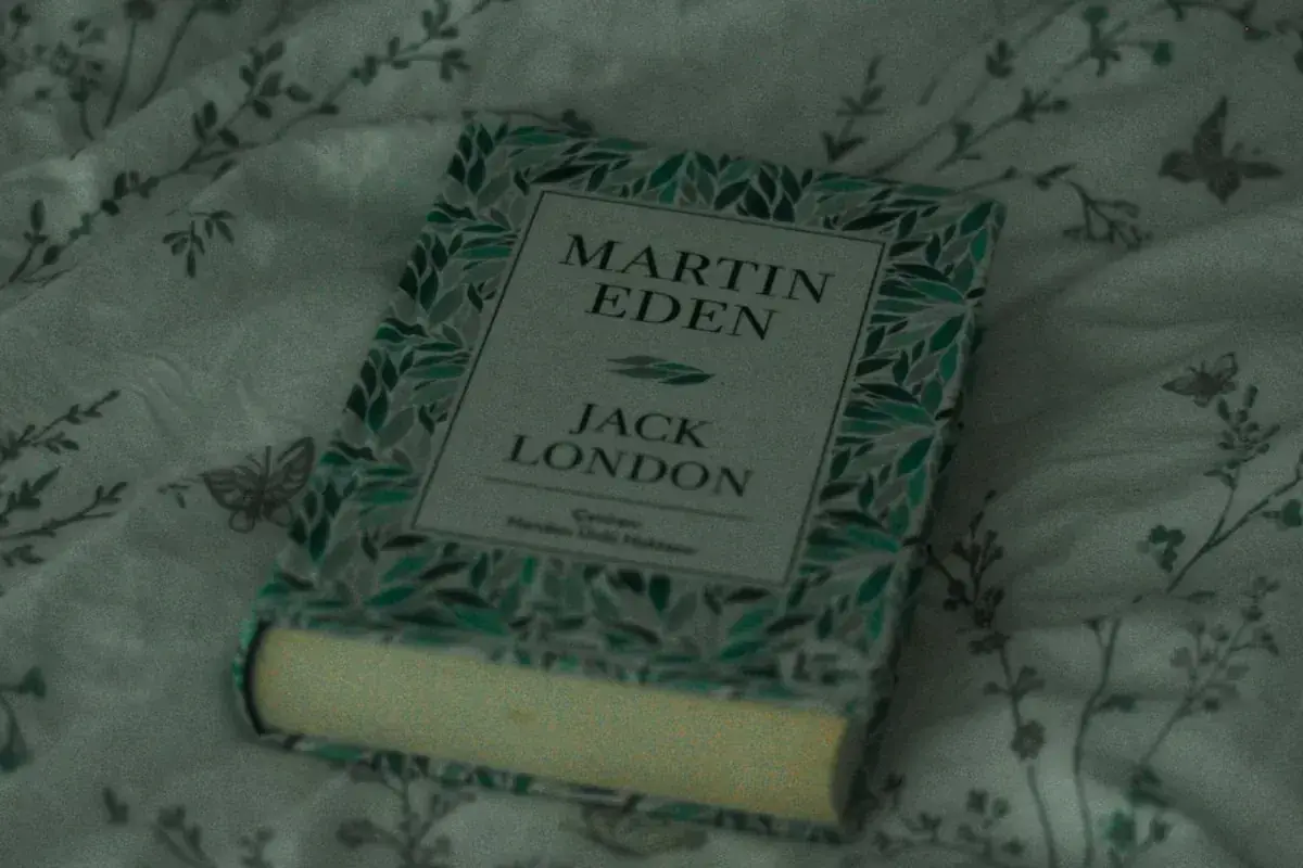 En bok med titeln "Martin Eden" av Jack London ligger på ett mönstrat tyg. Vad betyder roman? Denna bok är ett klassiskt exempel.