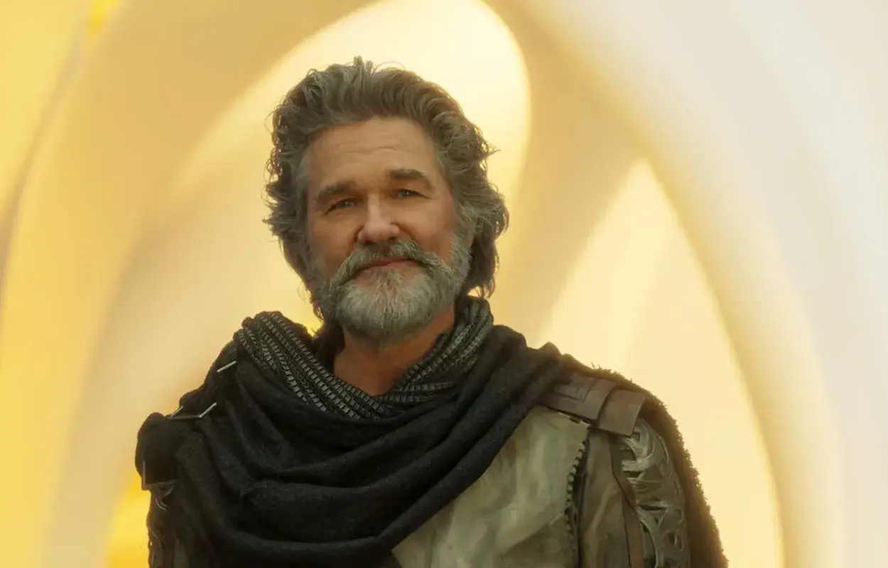 Kurt Russell med grått hår och skägg, klädd i en mörk sjal och rustning. En ikonisk skådespelare som syns i många filmer med Kurt Russell.