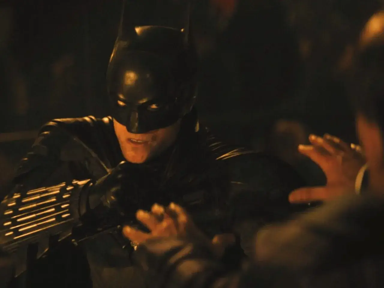 Batman i mörk dräkt, redo för strid i en av filmerna med Batman. En hand syns i förgrunden.