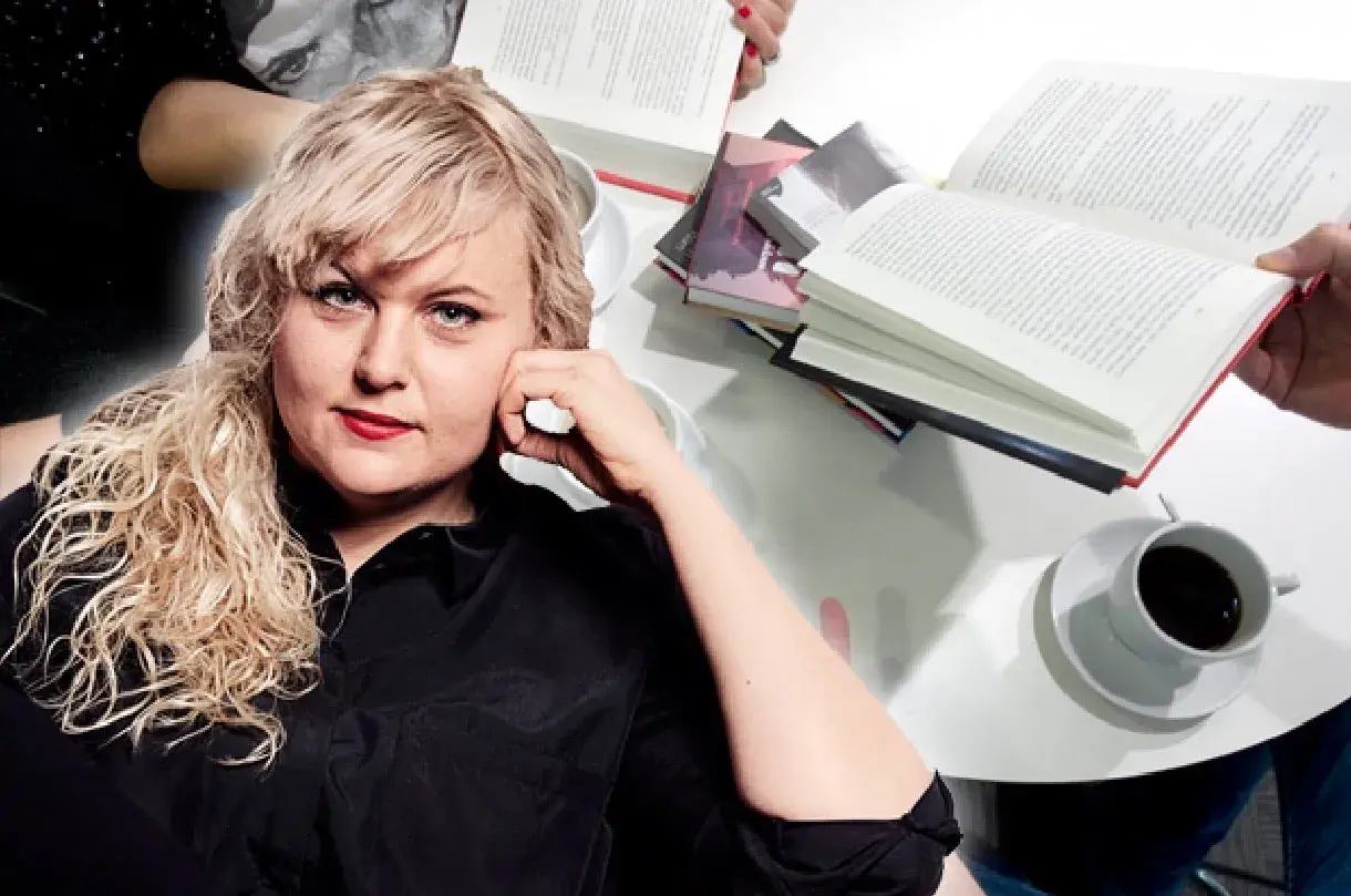 Johanna Thydell sitter vid ett bord med böcker och kaffe.
