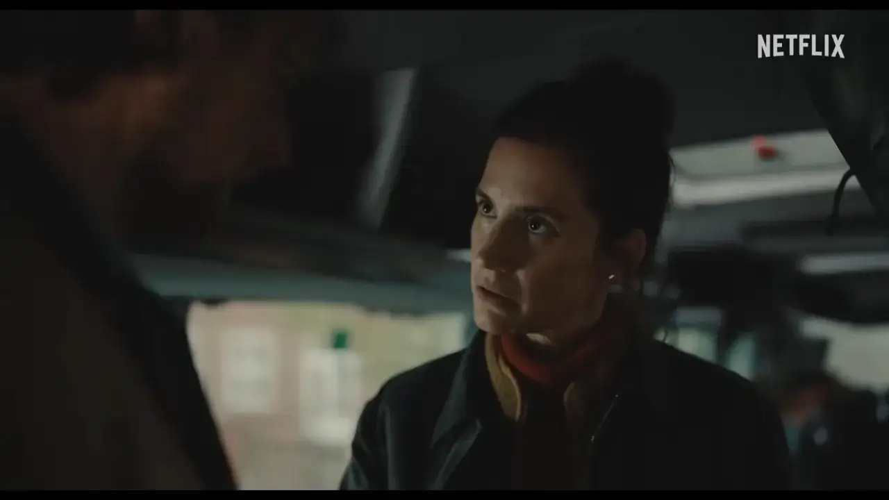 En kvinna med uppsatt hår och en röd polotröja tittar intensivt. Hon är en del av rollistan i Kastanjemannen, en spännande Netflix-serie.