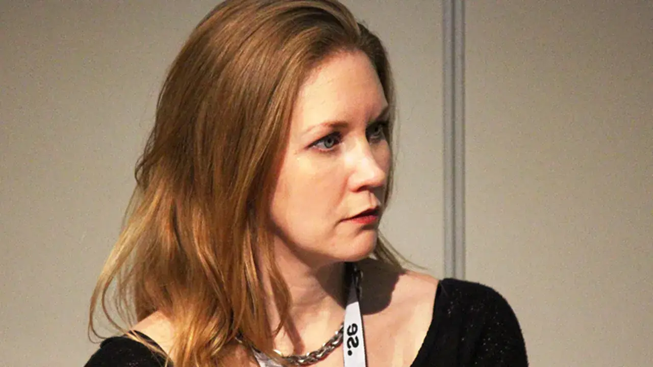 Anna Hedelius, med sitt blonda hår och blå ögon, bär ett silverfärgat halsband och en vit namnskylt.