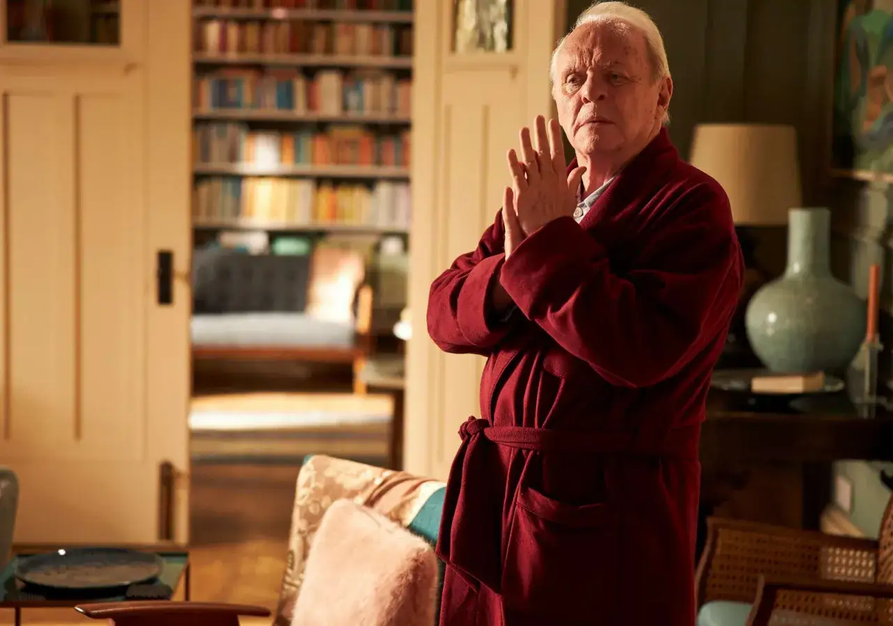 Anthony Hopkins i sin vinr&ouml;da morgonrock, med h&auml;nderna kn&auml;ppta, i ett rum med bokhyllor. En gripande skildring av Anthony Hopkins demens.