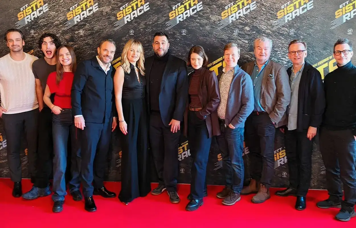 Rollistan i ett sista race samlad på röda mattan. En grupp skådespelare och filmskapare poserar framför en bakgrund med filmens logotyp.
