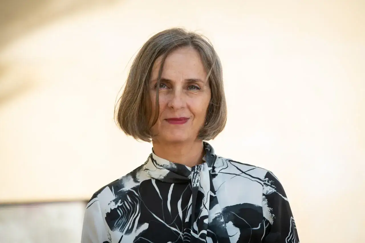 Porträtt av Susanna Alakoski, författare, med en mönstrad blus och grått hår.