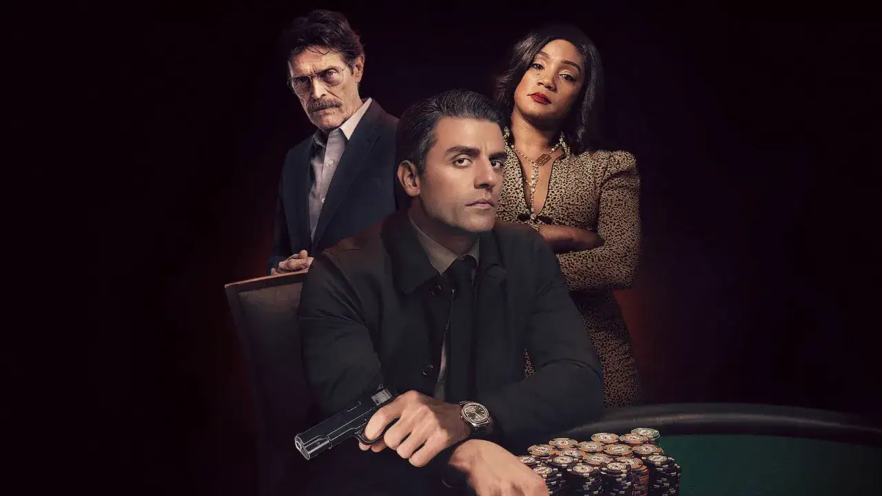 Oscar Isaac som the card counter, med Tiffany Haddish och Willem Dafoe. En pistol ligger på bordet bland marker.