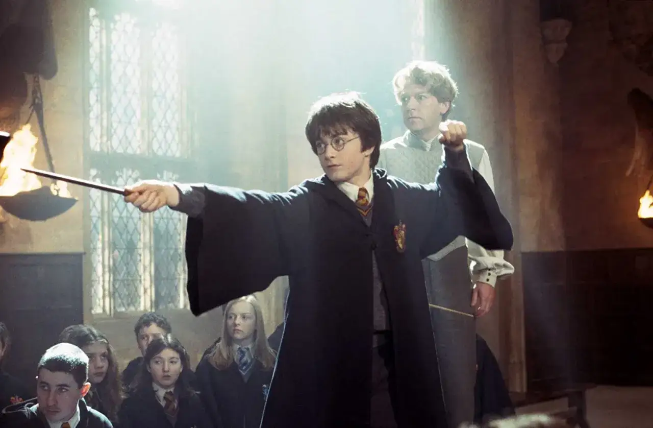 Harry Potter övar en trollformel i en lektionssal, med läraren Lockman i bakgrunden. En scen från harry potter-filmerna.