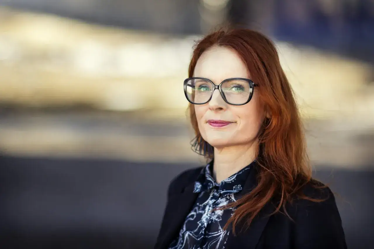 Jenny Aschenbrenner, med sitt r&ouml;da h&aring;r och glas&ouml;gon, ler mot kameran.