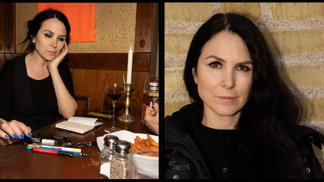 Nina Hemmingsson, med sitt karakteristiska uttryck, sitter vid ett bord med konstnärsmaterial. Hennes partner ser ut att vara en kreativ själ.