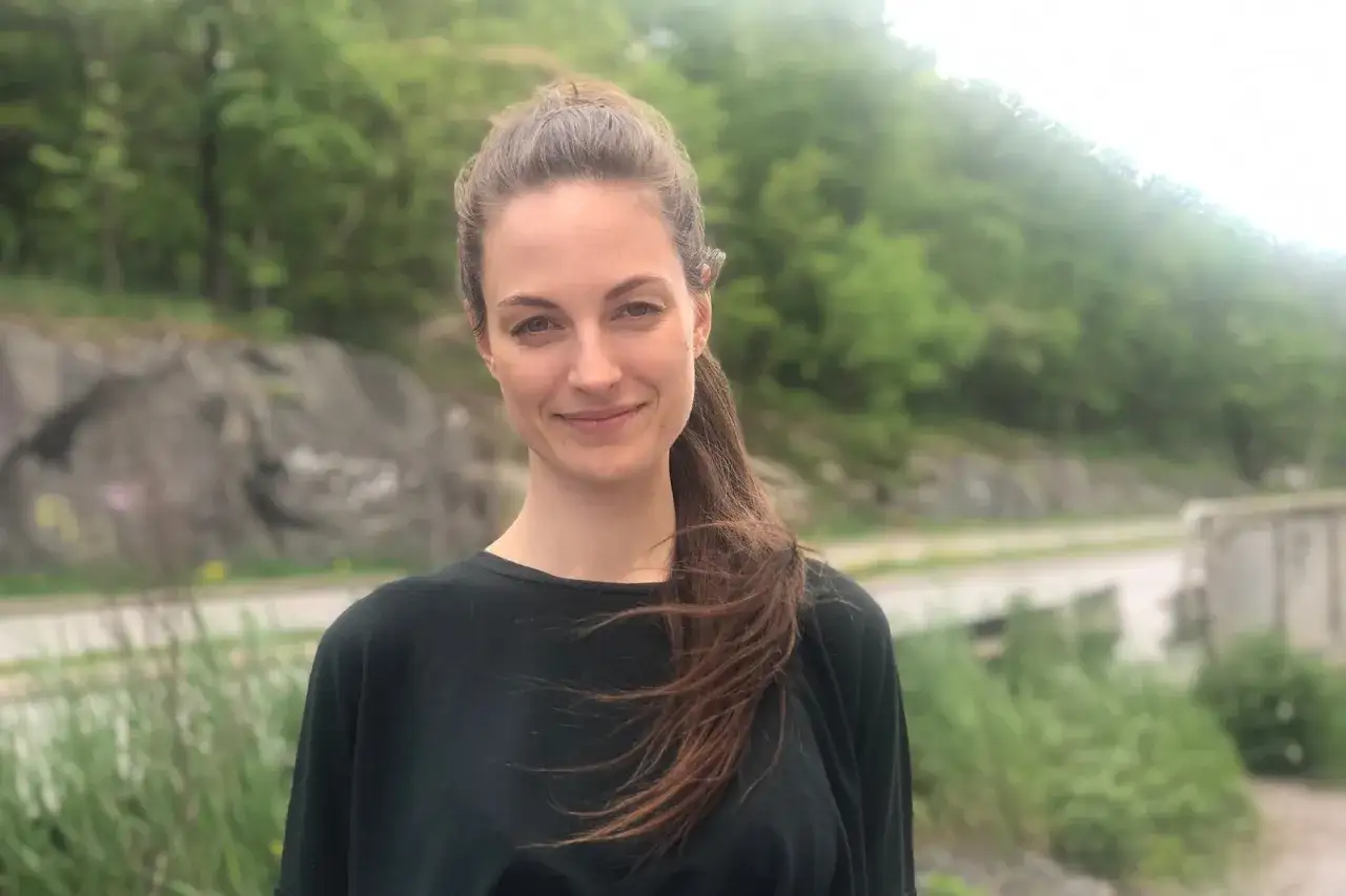 Petra Wahlgren ler mot kameran utomhus, med en grönskande bakgrund.