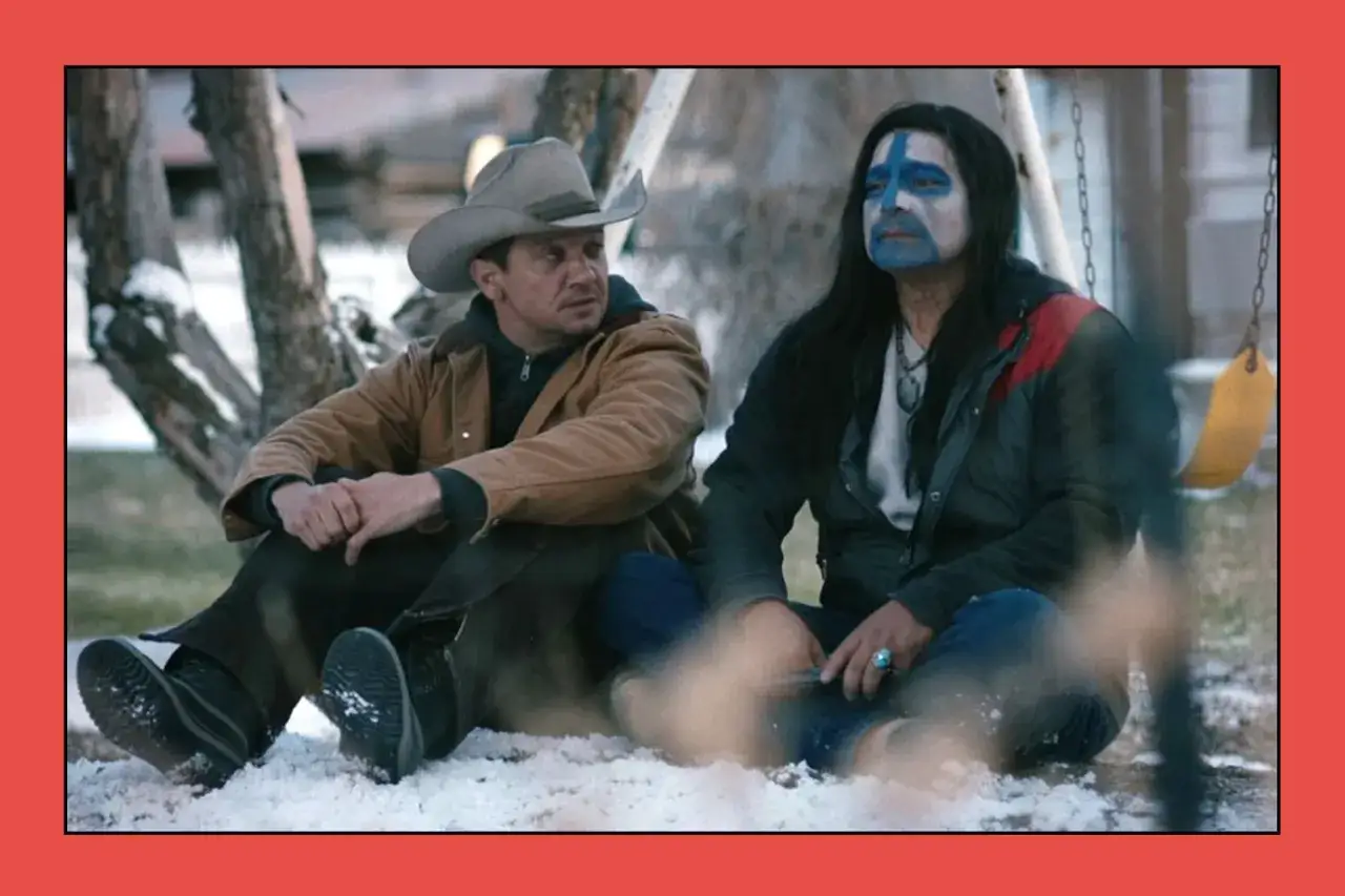 Jeremy Renner och Gil Birmingham i en scen från Wind River. De sitter i snön, en med cowboyhatt, den andra med ansiktsmålning.