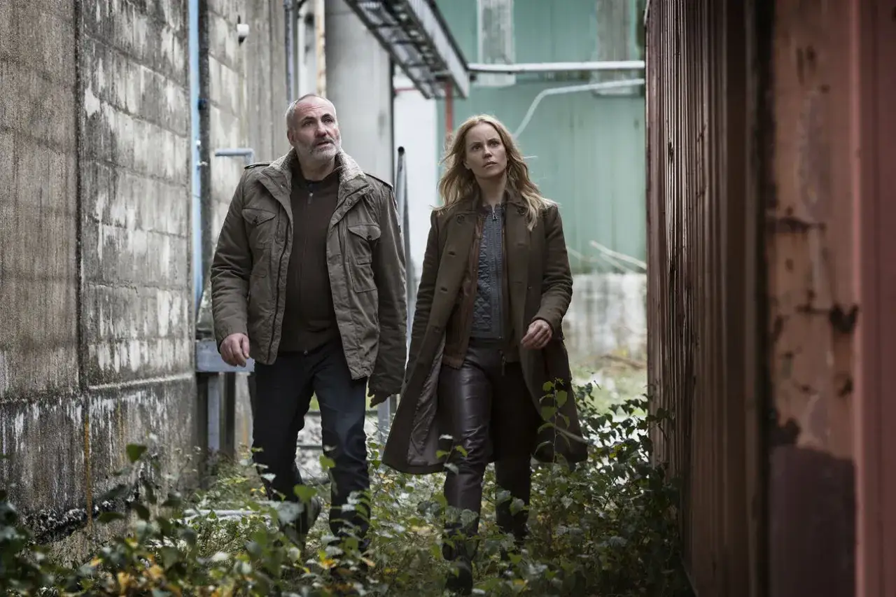 Två poliser, en man och en kvinna, går genom ett industriområde. Scen från en dansk kriminalserie.