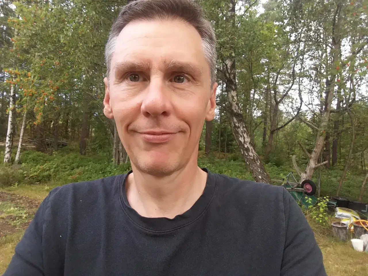 Johan Nilsson ler mot kameran i en lummig trädgård.
