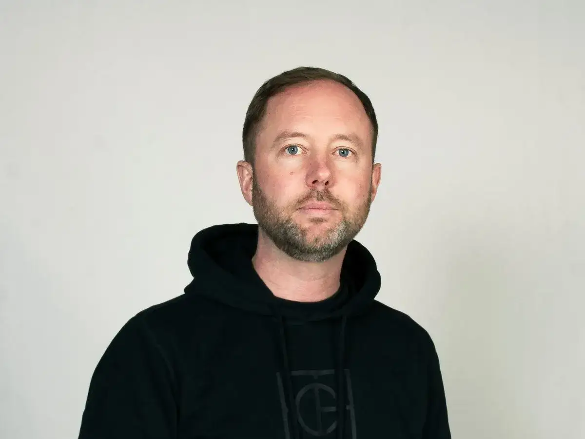 Daniel Holmgren, en man med blå ögon och skägg, bär en svart hoodie.