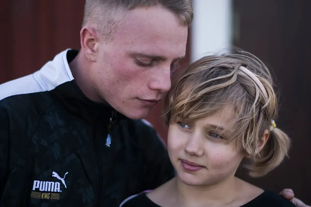 En ung man viskar något till en flicka. Kanske en scen från rollistan i Goliat.