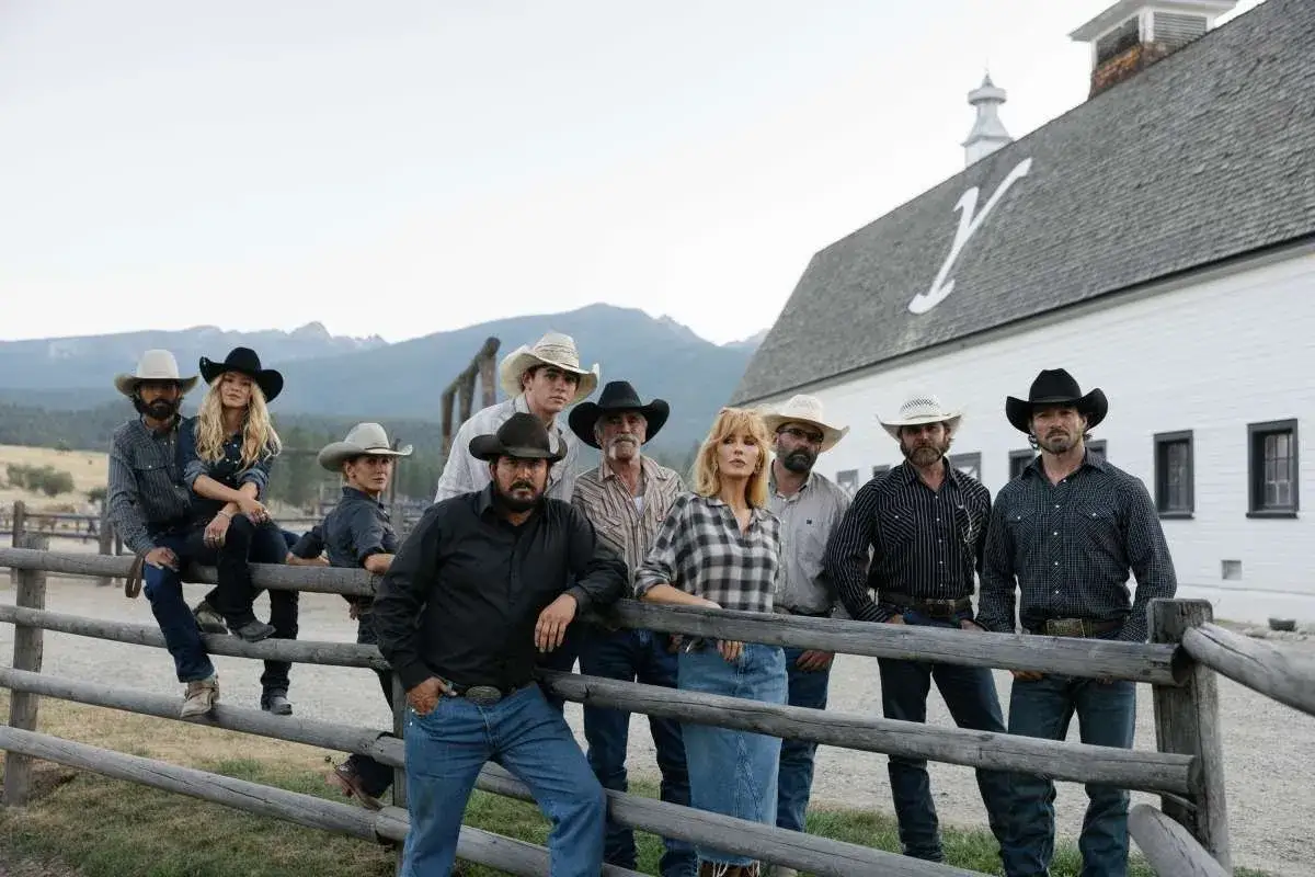 Familjen Dutton från Yellowstone-serien poserar framför en vit lada.