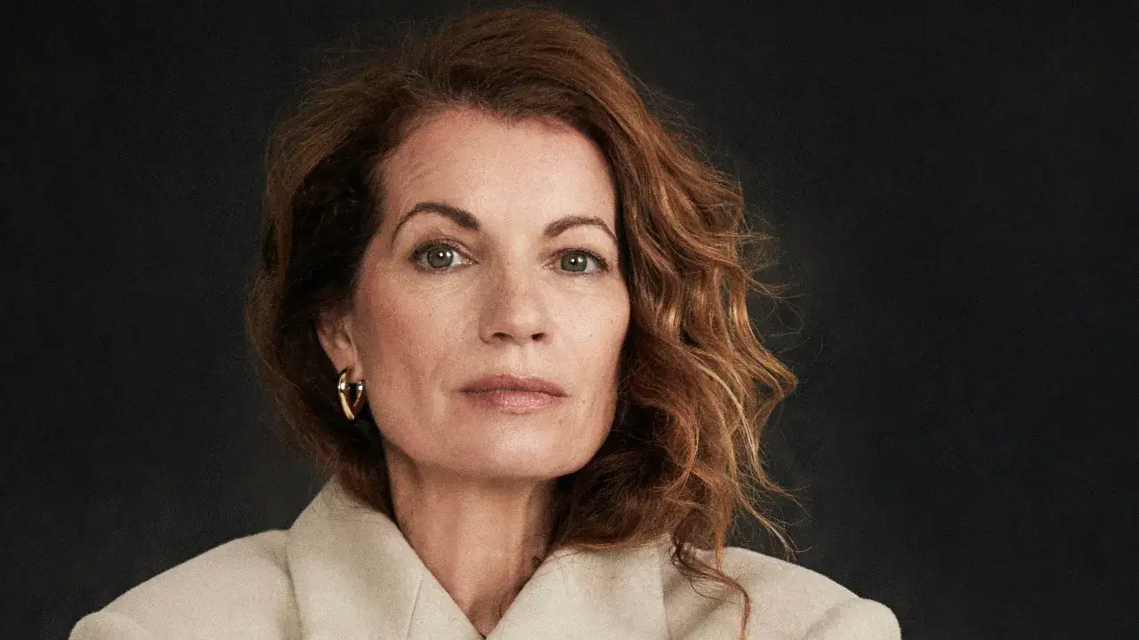 Alexandra Coelho Ahndoril, med sitt karaktäristiska röda hår och blick, bär en elegant ljus kappa.