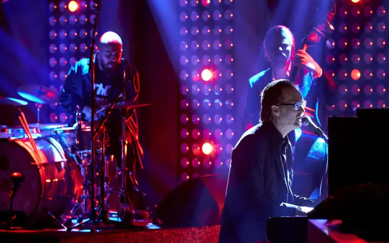 Matti Ollikainen spelar piano med ett band i bakgrunden.