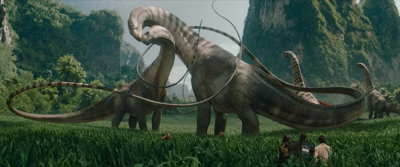 I en grönskande dalgång, likt ett nya jurassic park, betar flera långhalsade dinosaurier. I förgrunden skymtar tre personer som betraktar dem.