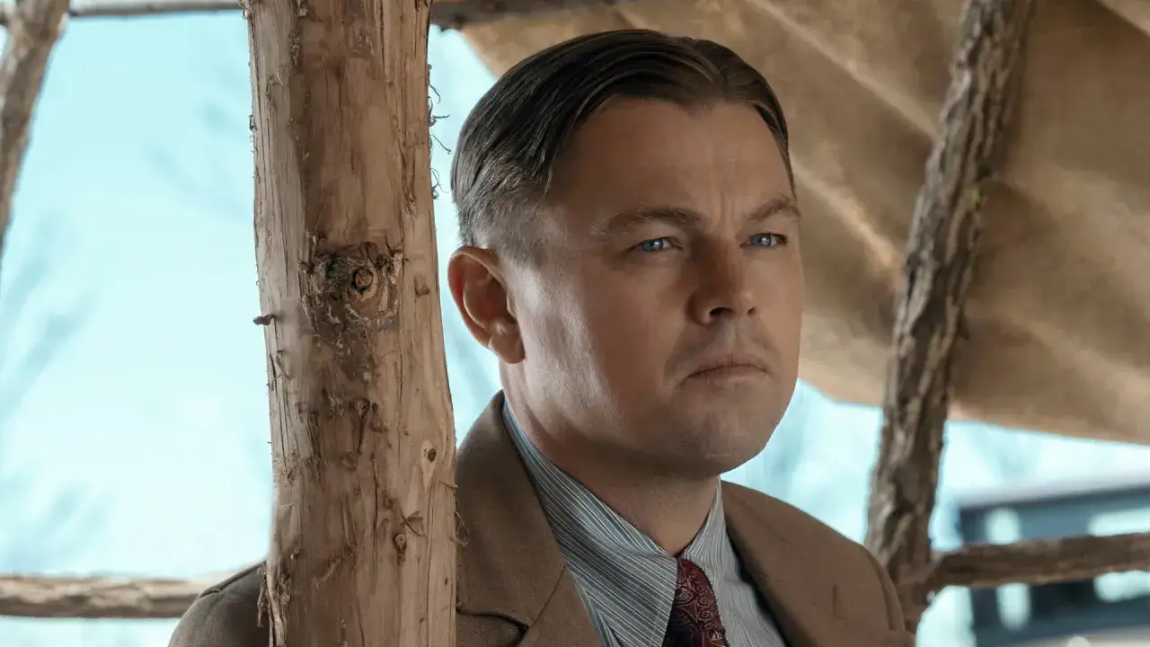 Leonardo DiCaprio i en brun kostym, med blå ögon och en fundersam blick. En scen från filmer med Leonardo DiCaprio.